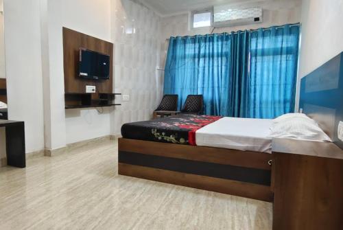 AyodhyaGoroomgo Hotel The Nirmala Palace Ayodhya-Near Ram Mandir的一间卧室配有一张带两把椅子的床和电视。