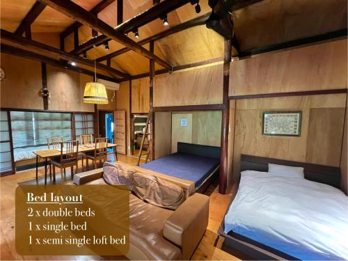 熊本SUMITSUGU HOUSE West的一间带两张床的房间和一间带桌子的用餐室