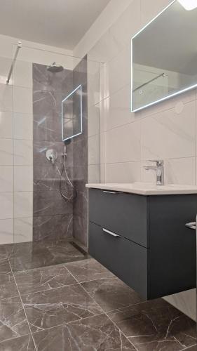 巴斯卡Santima Apartments的浴室配有盥洗盆和带镜子的淋浴