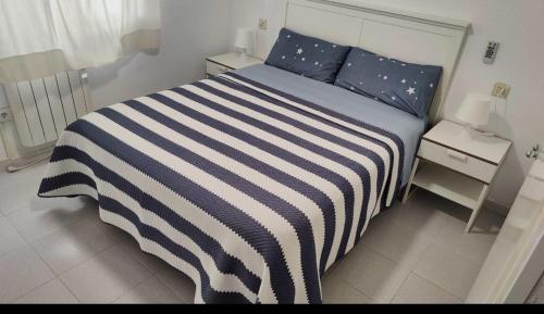 德拉塞尔瓦港Port de la Selva apartament的卧室内的一张带蓝色和白色条纹棉被的床
