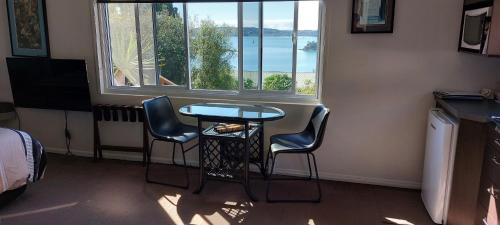 派西亚海湾之端旅馆的客房设有桌子、两把椅子和窗户。