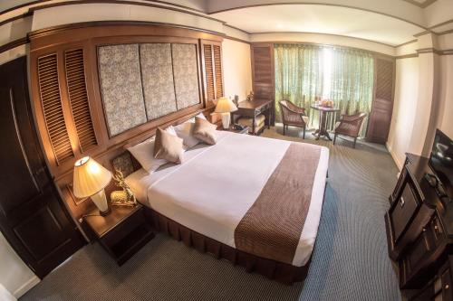 南邦Lampang Wieangthong的酒店客房设有一张大床和一张书桌。
