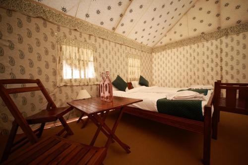 阿拉哈巴德Shivadya Camps MAHAKUMBH Mela的卧室配有一张床和一张桌子及椅子