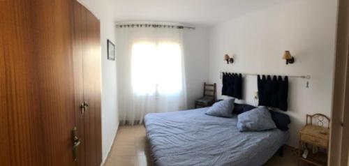 兰卡GRIFEU的一间卧室配有一张带蓝色床单的床和一扇窗户。