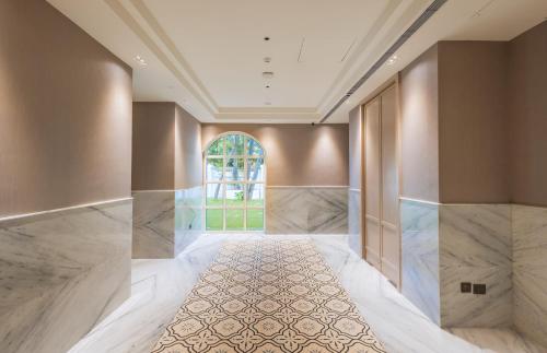 罗纳瓦拉Enrise by Sayaji Lonavala的空的走廊,铺有大理石地板,设有大窗户
