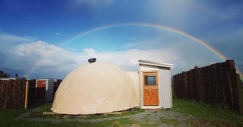 怀普Waipu Off-grid Eco Geodesic Glamping Dome的天空中带彩虹的大型圆顶帐篷