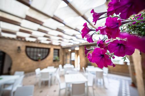 马里内拉La Rosa Hotel - Selinunte的配有桌子和白色椅子以及紫色鲜花的房间