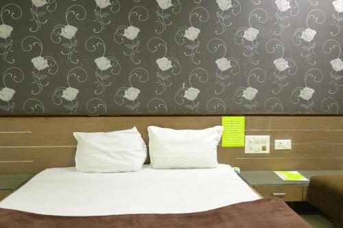 博帕尔Hotel Neelkanth , Bhopal的客房内的一张带白色枕头的床