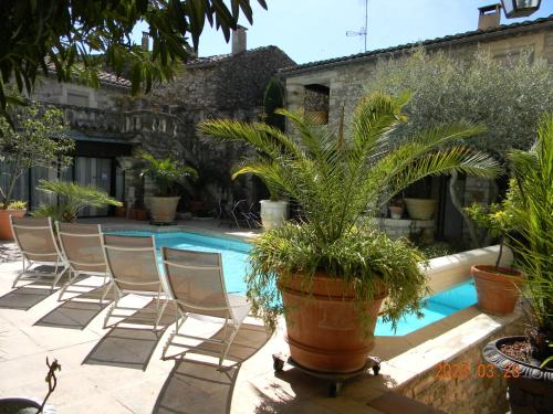 艾盖兹Le Castélas的一组椅子和一个种有植物的游泳池