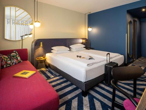 维也纳美居维也纳城市酒店的一间卧室配有一张大床和一张红色的沙发