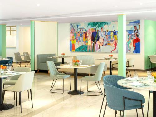 迪拜Queen Elizabeth 2 Hotel的一间带桌椅的餐厅以及一幅画