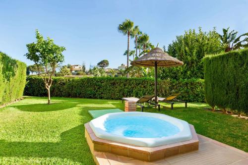 米哈斯科斯塔Wyndham Grand Costa del Sol的庭院内的热水浴池,配有遮阳伞