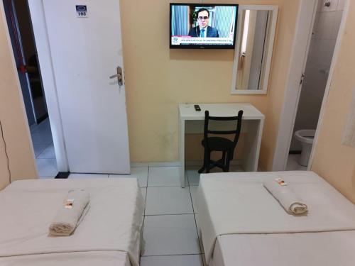 LagartoPOUSADA MEDITERRÂNEO的客房设有两张床和一台墙上的电视。