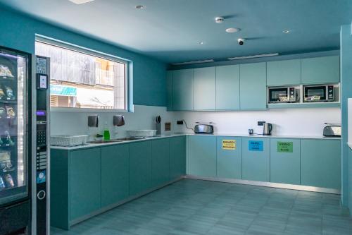 坎帕斯蒂利亚The Boc Hostels - Beach的一间设有蓝色橱柜和窗户的大厨房