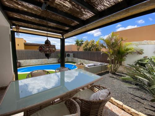 科拉雷侯Casa Rosalía的一个带玻璃桌椅的庭院和一个游泳池