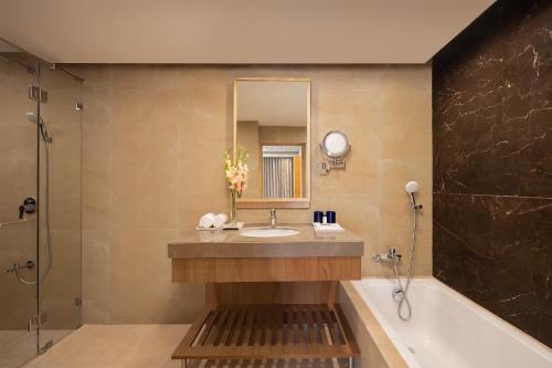 巴克塔普尔Fortune Resort and Wellness Spa - Member ITC's Hotel Group的一间带水槽、浴缸和镜子的浴室