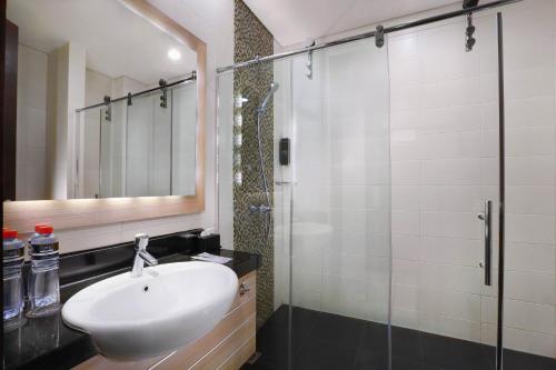 泗水Hotel Neo Gubeng by ASTON的一间带水槽和玻璃淋浴的浴室