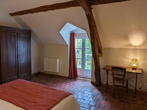 ThenayMaison dans belle longère - La Serrerie的一间卧室配有一张床、一张书桌和一个窗户。