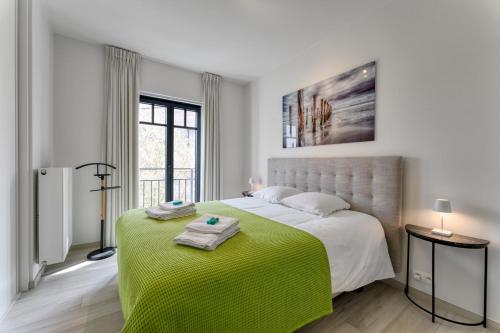 克诺克－海斯特Zonnig Luxueuze Appartementen La Coronne的白色卧室配有一张带绿毯的大床