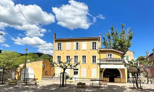 La RoquebrussanneHôtel de la Loube的前面有长椅的大型黄色建筑