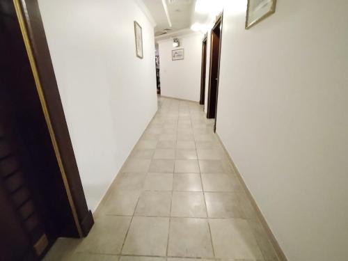 吉达فندق مدهال的长长的走廊设有白色的墙壁和瓷砖地板