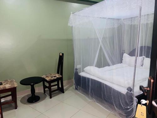 坎帕拉Suzie hotel Kampala hotel的一间卧室配有一张带桌子和凳子的天蓬床