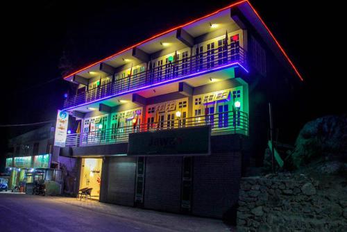 锡卡都Al Jannat Hotel & Relax Inn Guest House Skardu的一座晚上亮着五颜六色灯光的建筑