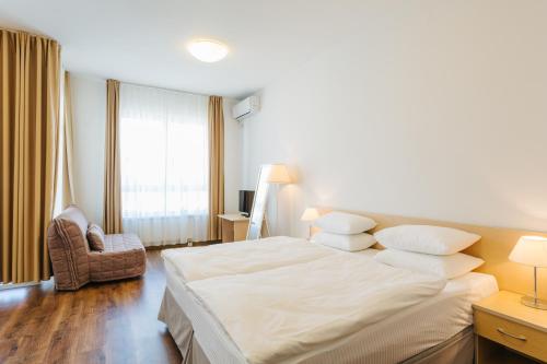 阿德勒伊梅莱汀斯基摩尔思科公寓酒店的卧室配有一张白色大床和一把椅子
