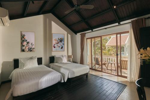 Hiếu NhơnEn Retreat Villa Hoi An的一间带两张床的卧室和一个阳台