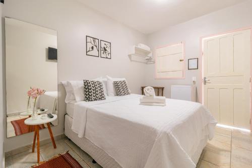 皮雷诺波利斯Pousada Lara的白色的卧室配有白色的床和一张桌子