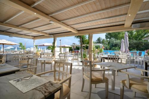 卡沃斯Cavomarina Beach- Adults Only的一间带桌椅的餐厅和一个游泳池