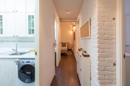马德里Residencia Salamanca的厨房设有洗衣机和烘干机,毗邻砖墙