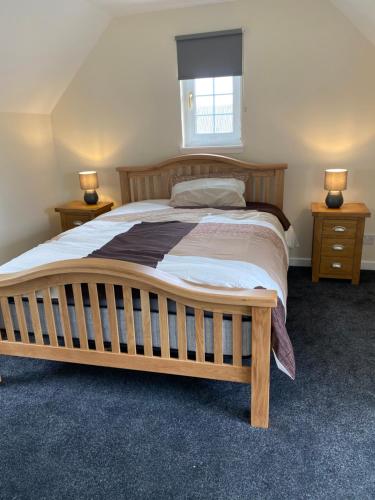 柯克纽顿WHITEHILL STABLES的一间卧室配有一张带2个床头柜的大型木床