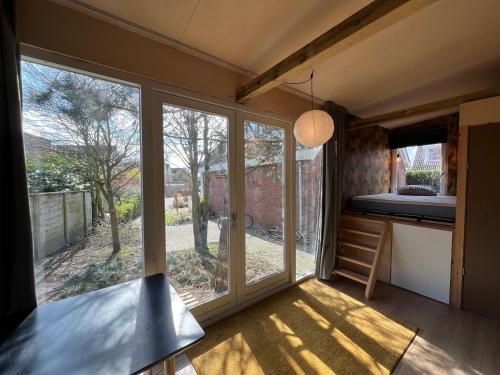 莱利斯塔德A tiny house close to nature - Amsterdam region的一个小房子,设有大窗户和一张床