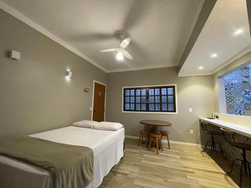乌巴图巴Chilli Brasil Suite的一间卧室配有一张床、一张桌子和一个窗户。