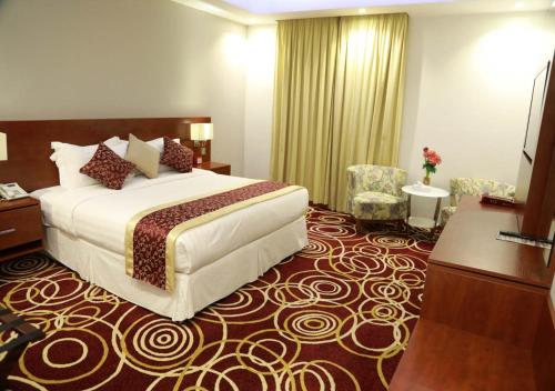 吉达Wow Hotel Jeddah的酒店客房,配有一张床和两把椅子