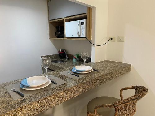 若昂佩索阿Bela Hospedagem - Marinas Flat - Excelente localização na orla de Cabo Branco的厨房柜台配有盘子、玻璃杯和微波炉
