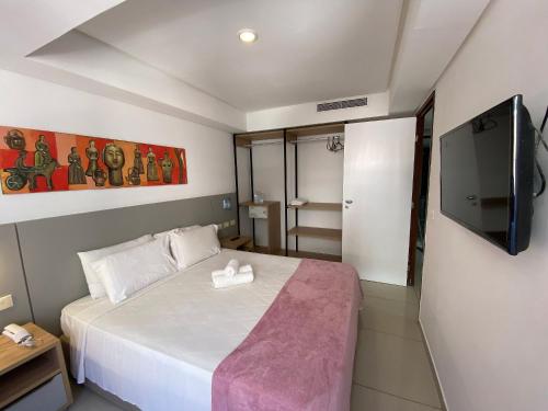 若昂佩索阿Bela Hospedagem - Marinas Flat - Excelente localização na orla de Cabo Branco的一间卧室配有一张床和一台平面电视