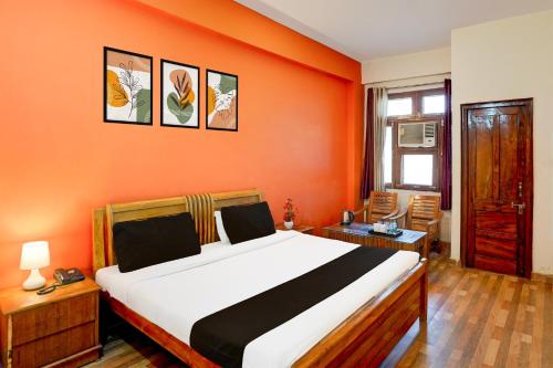 哈里瓦OYO Ranipur Mod Near Prem Ashram的一间卧室配有一张带橙色墙壁的大床