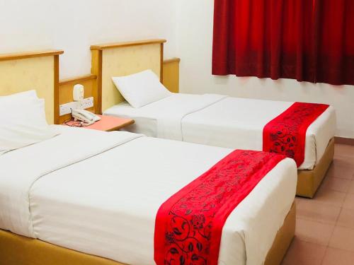 瓜拉丁加奴印丹海滩度假酒店的一间设有两张红色和白色床单的房间
