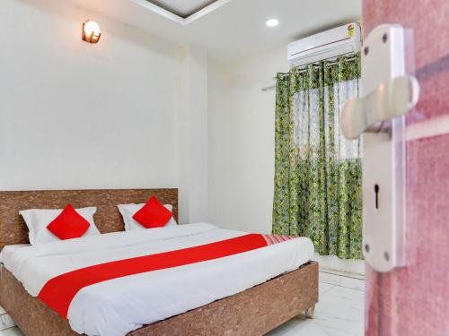 博帕尔OYO Hotel Shivansh的一间卧室配有一张带红色枕头的床和一扇窗户