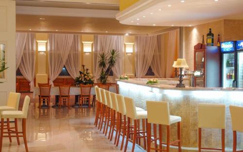 皮塞克白玫瑰大酒店的餐厅设有酒吧、椅子和柜台