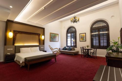 马六甲Hotel Puri Melaka的一间卧室配有一张床、一张沙发和一张桌子