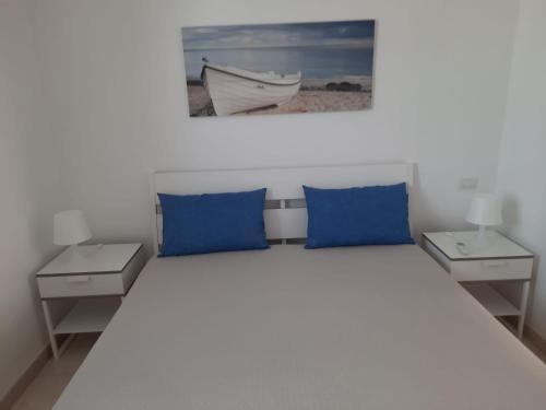 切萨雷奥港La Vela Apartaments - Porto Cesareo的一间卧室配有蓝色枕头,另一张床配有两张桌子