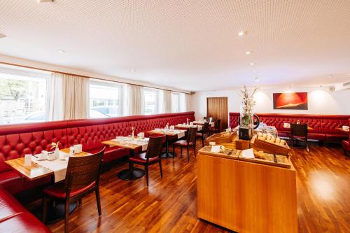 多恩比恩Sonne 1806 - Hotel am Campus Dornbirn的餐厅设有红色的隔间和桌椅