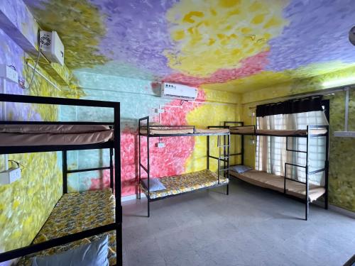 可瓦兰Santa Maria Hostel Kovalam的客房设有三张双层床和色彩缤纷的天花板。