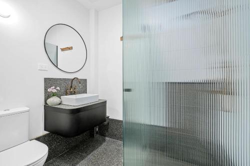 吉朗The Electric Hotel的浴室设有玻璃淋浴间、卫生间和水槽。