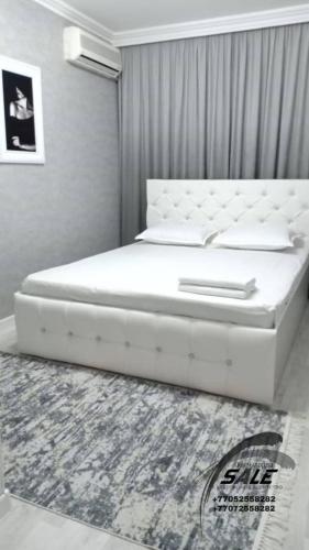 KooperatorЭлитная 2-комнатная квартира в районе Болашак的卧室内的一张白色床,铺着地毯