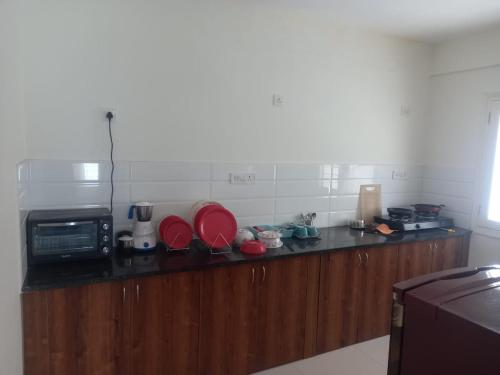 班加罗尔Windfall Service Apartment的厨房配有红色盘子和微波炉