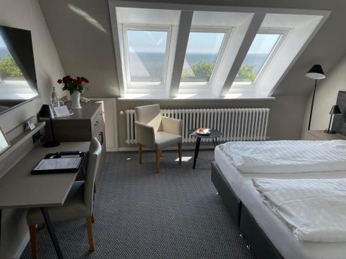 威克奥夫弗尔Kurhaus Hotel的酒店客房设有一张床、一张书桌和窗户。